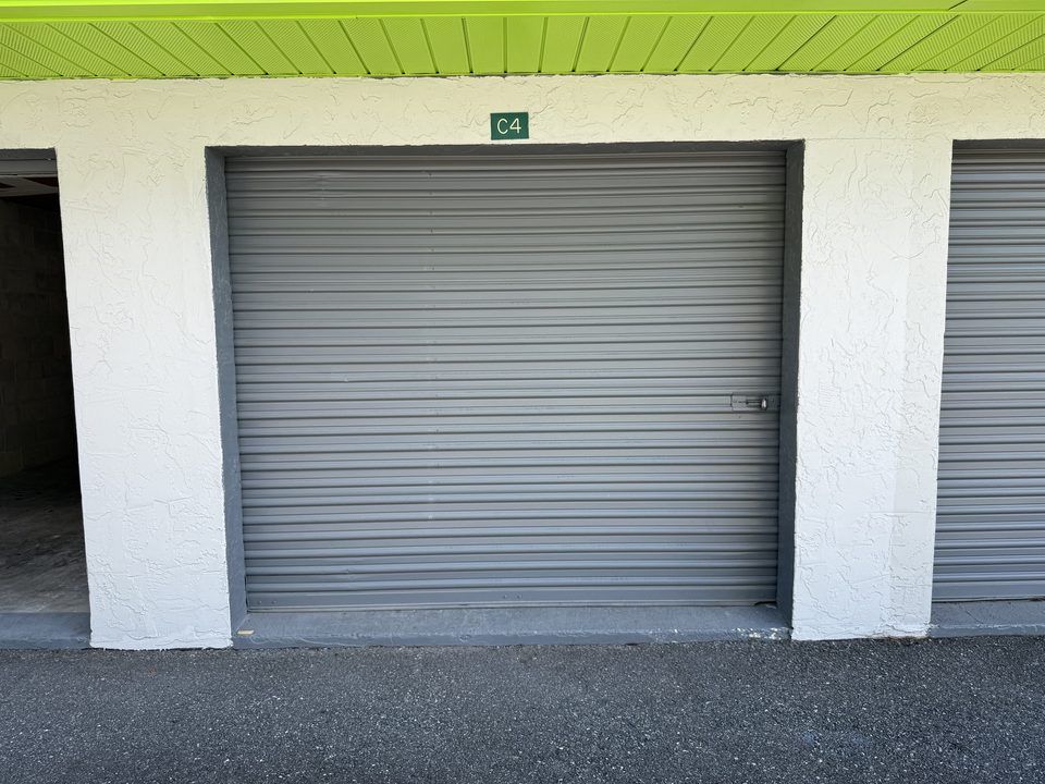 Close-up of a numbered drive-up storage unit with grey roll-up door and lime-green-trimmed eaves at Cortez Self Storage, Brooksville, FL.